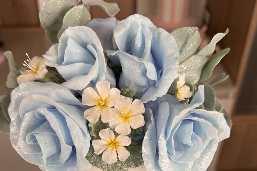 Rosas celestes y jazmines en pasta de goma con hojas de eucalipto coronando el pastel